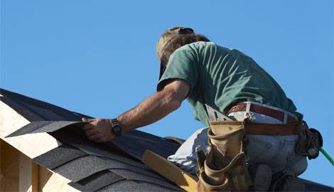 Workman on roof carefully placing shingles